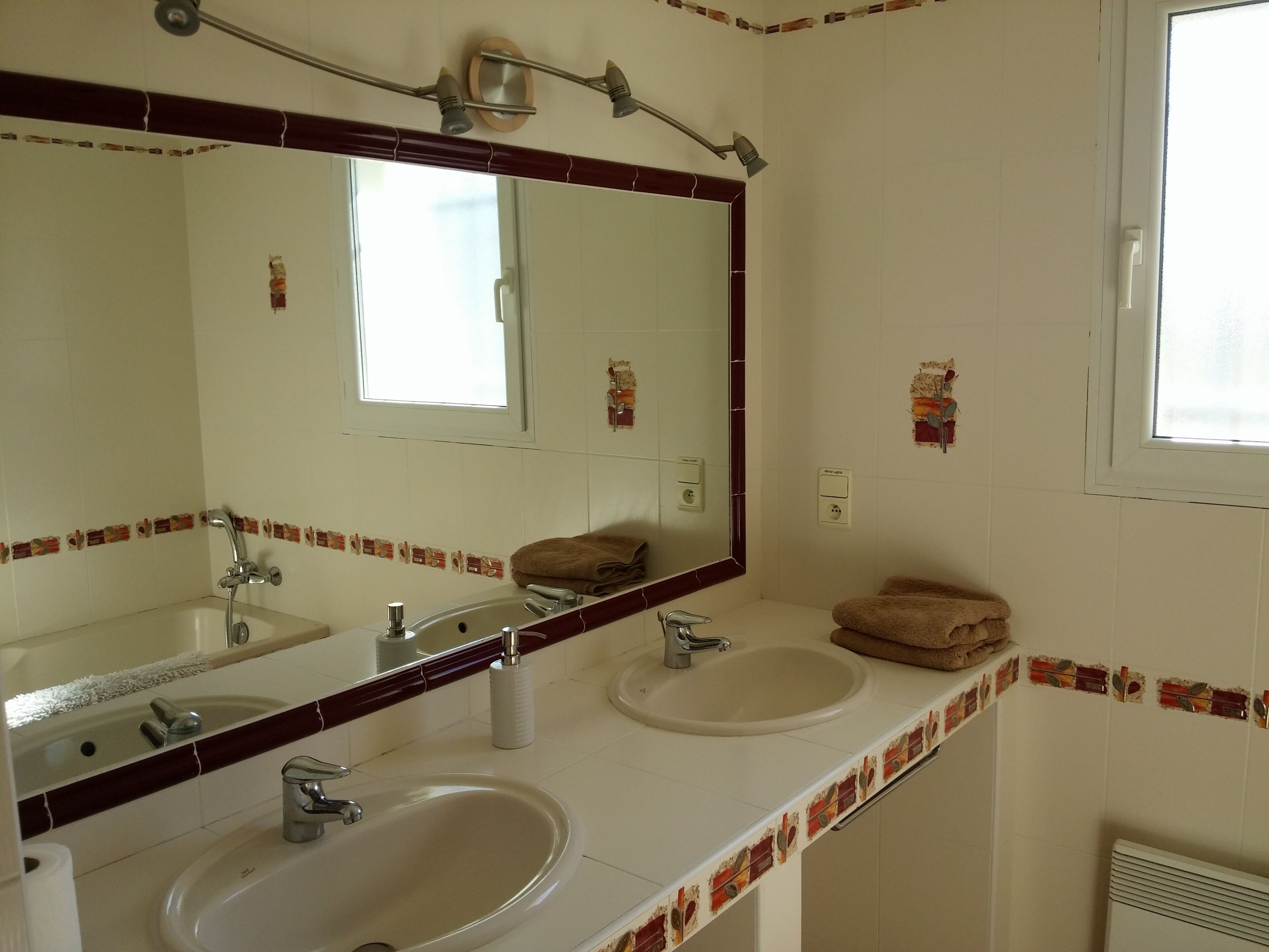 A bathroom with two sinks, a large mirror, and a window.