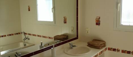 A bathroom with two sinks, a large mirror, and a window.