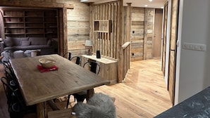A cozy living area with a wooden wall, a sofa, a dining table with chairs, and a fluffy rug. - Apt. duplex of 72 m2, 3 bedrooms, in the heart of Alpe d'Huez garden (Huez)