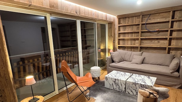 A cozy living room with a sofa, a chair, a coffee table, and a small stool. There is a sliding glass door leading to a balcony. - Apt. duplex of 72 m2, 3 bedrooms, in the heart of Alpe d'Huez garden (Huez)
