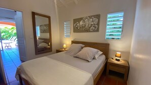 A bedroom with a bed, two bedside tables, a mirror, and artwork on the walls.