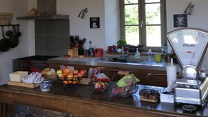 A kitchen with a stove, sink, and various kitchen items. There is a window with a view of greenery outside. - Charming house in the countryside close to the sea (Saint-Cyr-En-Talmondais)