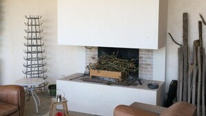 A living room with a fireplace, leather sofas, a metal table, and a metal rack. - Charming house in the countryside close to the sea (Saint-Cyr-En-Talmondais)