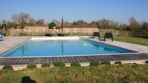 A rectangular swimming pool with a wooden deck surrounding it, a wooden fence in the background, and a clear blue sky. - Charming house in the countryside close to the sea (Saint-Cyr-En-Talmondais)