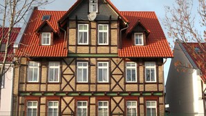 Ett traditionellt hus med korsvirkesfasad, brant tak och många fönster.