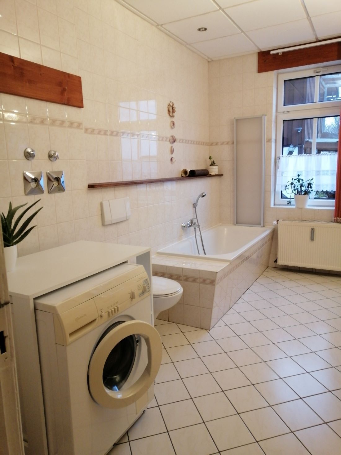 A modern bathroom with a washing machine, toilet, and bathtub.