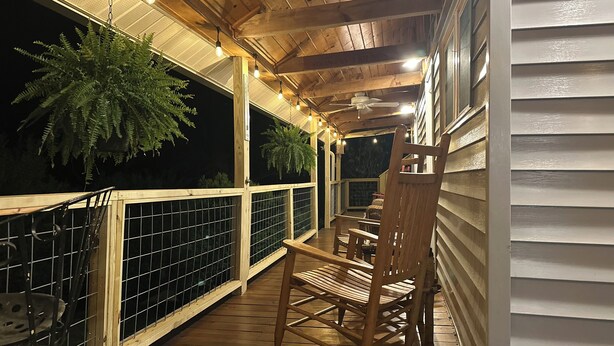 A wooden deck with a rocking chair and a table, surrounded by a wooden railing and potted plants. - Pet friendly,cozy cabin near Tail of the Dragon.Paved driveway & covered parking (Robbinsville)