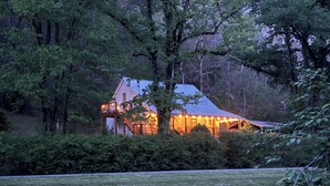 A house with a porch, surrounded by trees and a grassy area. - Pet friendly,cozy cabin near Tail of the Dragon.Paved driveway & covered parking (Robbinsville)