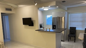Una cocina moderna con isla integrada, televisor de pantalla plana y refrigerador de acero inoxidable.
