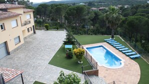 Une propriété résidentielle dotée d’une piscine, d’une terrasse en pierre et offrant une vue sur les collines environnantes.