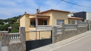 Une maison à deux étages avec un mur en pierre et un portail noir.