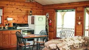 Een gezellig keuken in blokhutstijl met houten wanden, een koelkast, fornuis en een eettafel met stoelen.