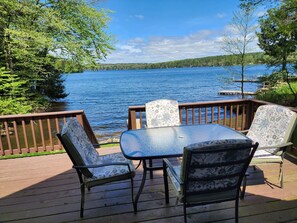A deck with a table and chairs overlooking a lake, surrounded by trees. - Galway Lakefront Retreat (Broadalbin)