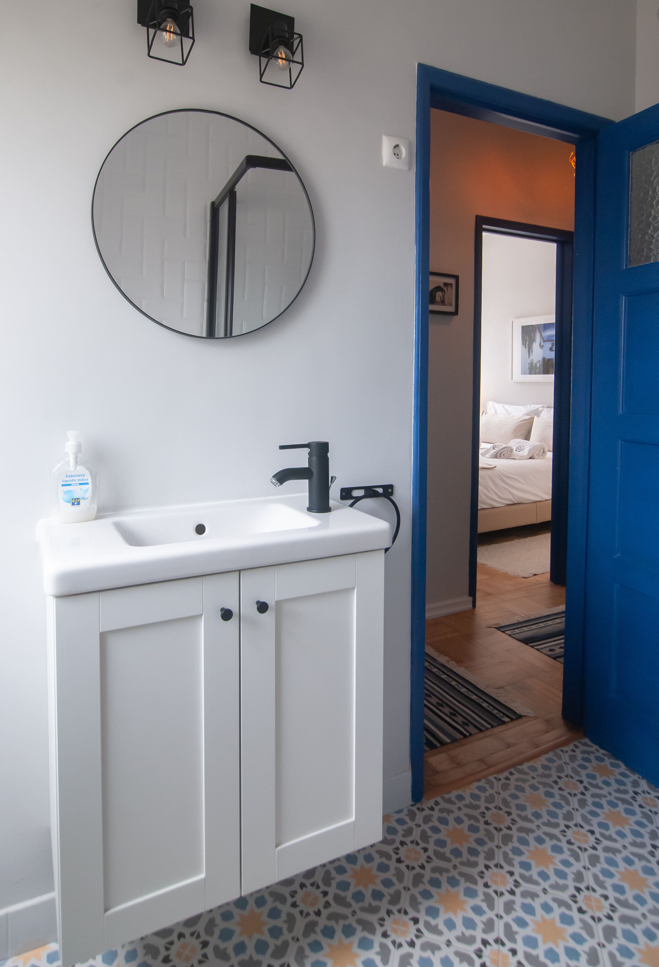A bathroom with a white sink, a mirror, and a bottle of soap.