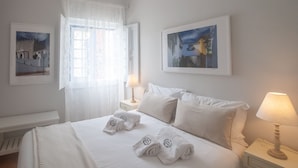 Una habitación de hotel con una cama, dos lámparas de noche y dos cuadros en las paredes.