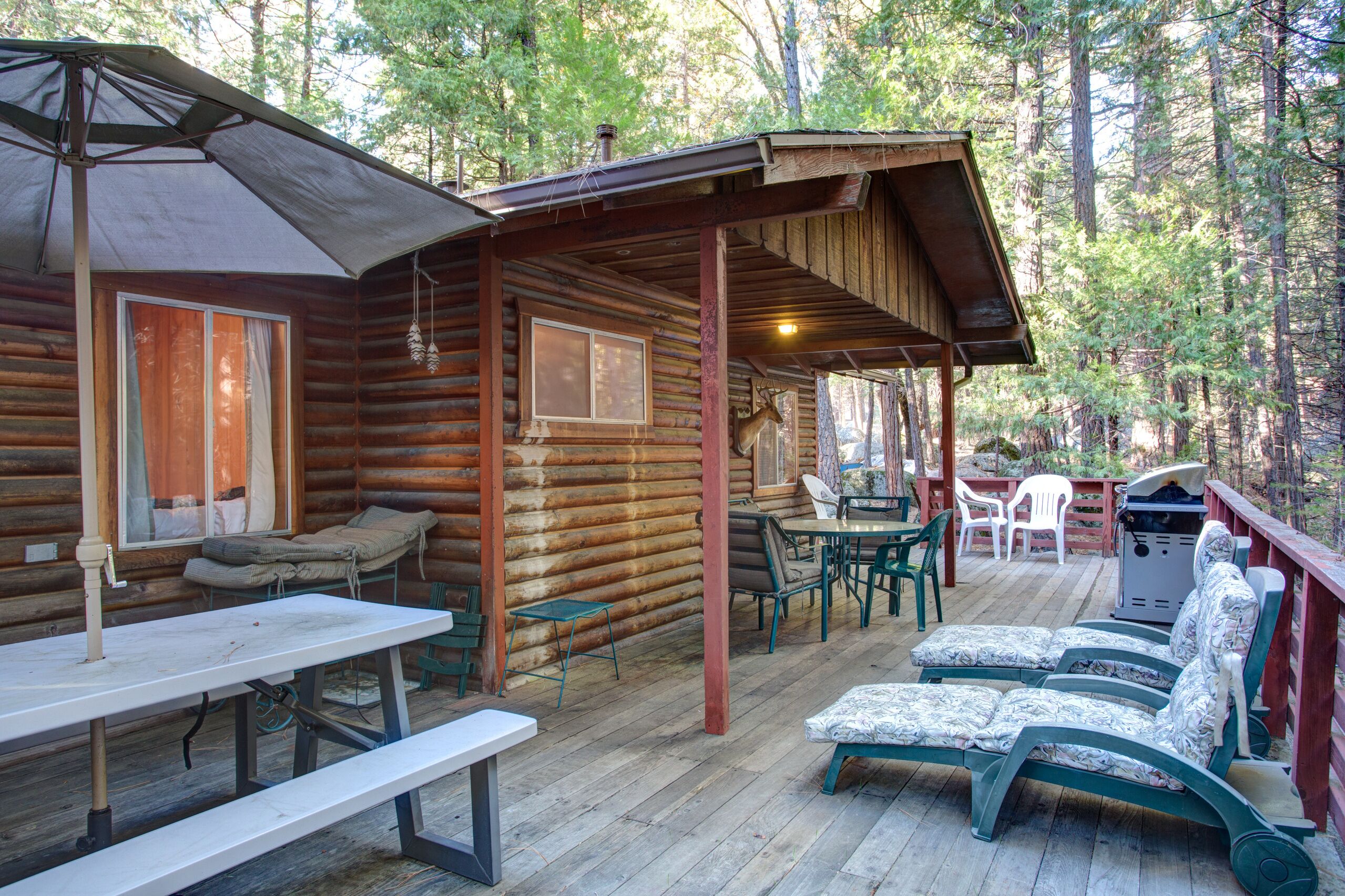 A log cabin with a deck, outdoor seating, and a table.