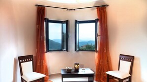 A room with two open windows, a table with decorative items, and two chairs. - Your secret haven, where nature paints... close to dream sandy beaches (Kato Pavliana)