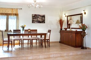 A dining area with a wooden table and chairs, a cabinet with decorative items, and a painting on the wall.