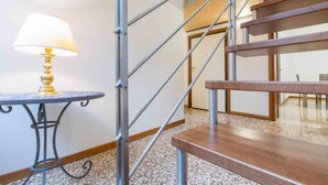 A staircase with metal railings and wooden steps, a round table with a lamp, and a carpeted floor.