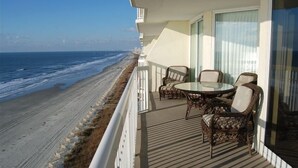 Ein Balkon mit Korbmöbeln mit Blick auf einen Strand.