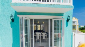 A two-story building with a balcony, a sliding glass door entrance, and outdoor furniture.