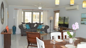 A living room with a sofa, dining table, chairs, and a TV.