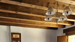 A neatly made bed with red pillows, a wooden ceiling, a small table with a lamp, and a window with a wooden shutter. - El Hogar del Fresno, charming tourist accommodation in Pedraza (Matabuena)