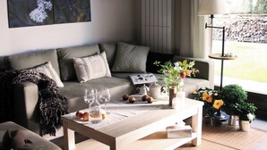 A cozy living room with a grey sofa, a wooden coffee table with snacks and drinks, a vase with flowers, and a lamp. - El Hogar del Fresno, charming tourist accommodation in Pedraza (Matabuena)