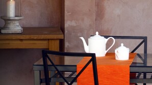 A table with a white teapot and a white sugar bowl, a candle in a glass holder, and a chair with a black frame. - El Hogar del Fresno, charming tourist accommodation in Pedraza (Matabuena)