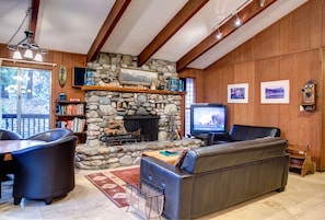 A cozy living room with a stone fireplace, leather furniture, and a television.