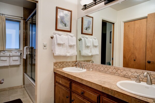 A bathroom with two sinks, a large mirror, and a shower.