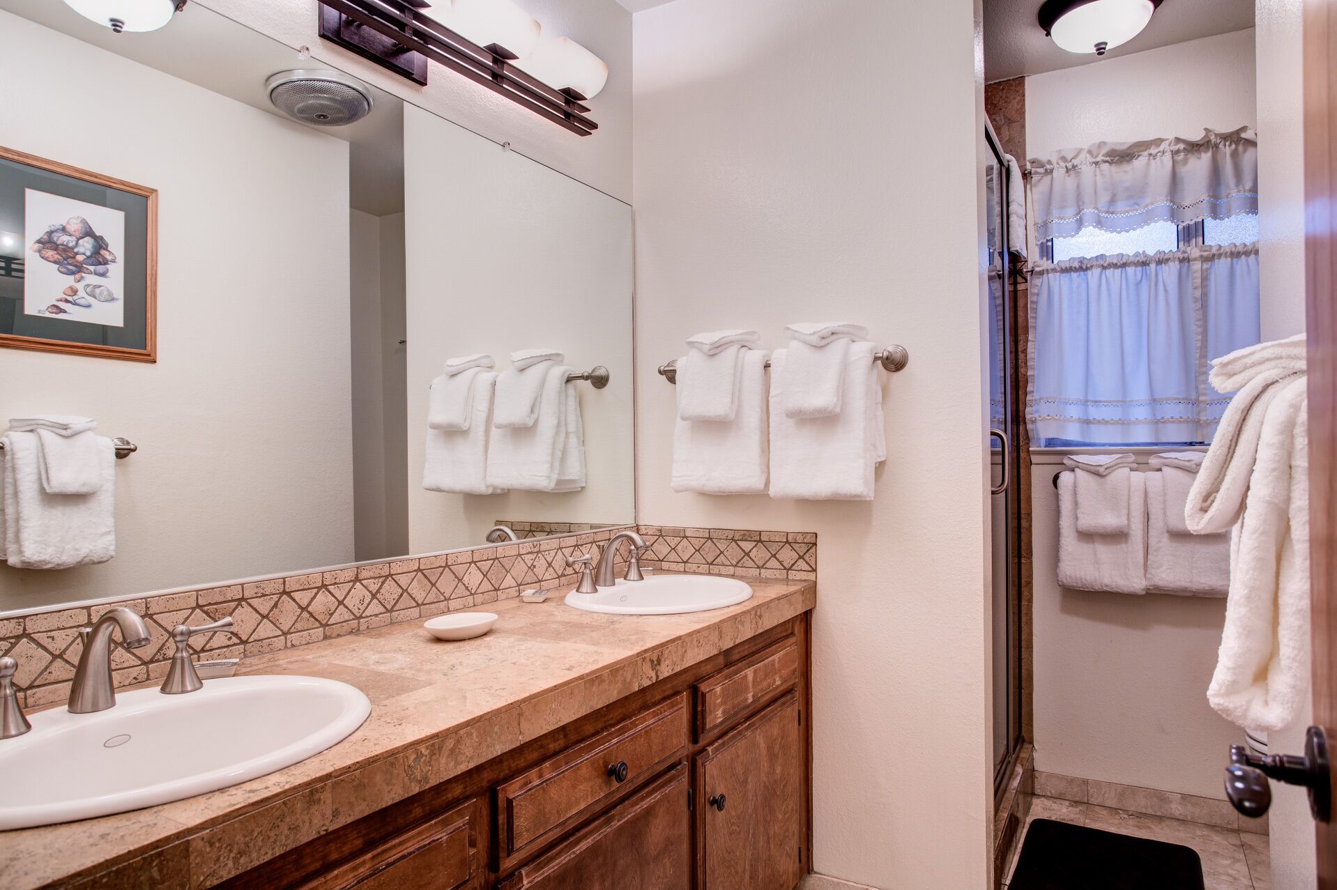 A bathroom with two sinks, a shower, and a tiled backsplash.
