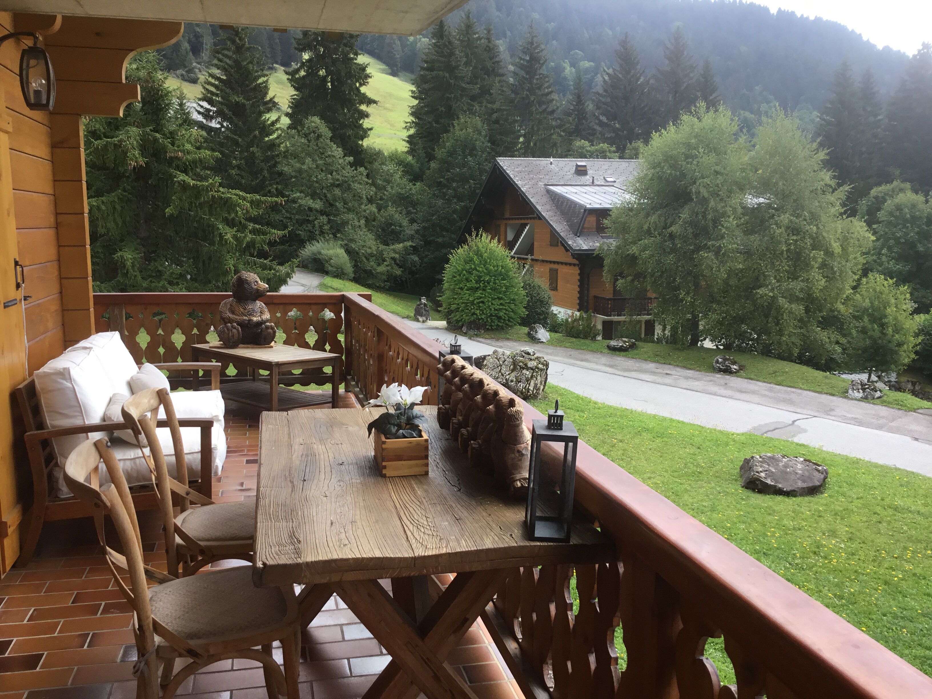 A wooden deck with a table and chairs, surrounded by a railing with bear sculptures.