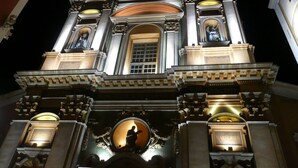 Un edificio imponente con arquitectura clásica, que presenta columnas ornamentadas, una cúpula central y estatuas iluminadas.