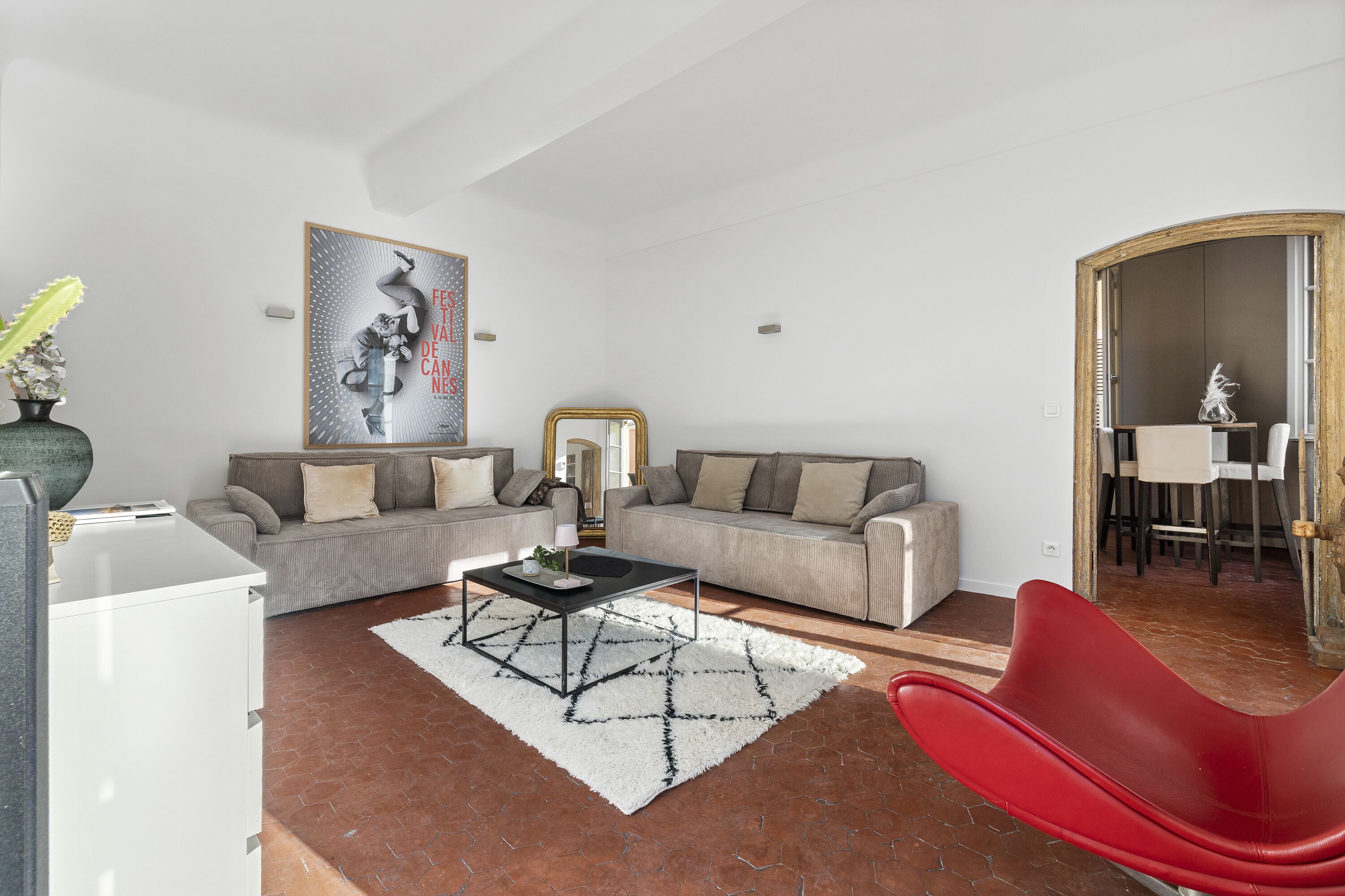A modern living room with a sofa, a coffee table, a red chair, and a painting on the wall.