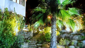 A well-lit outdoor area with a palm tree, stone steps, and a lounge chair. - Peaceful family villa with private pool & magnificent views, nr. perfect beaches (Calonge)