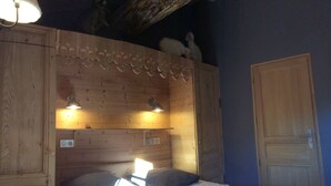 Ein Zimmer einer Holzhütte mit einem Bett, zwei Nachttischlampen, einer Holztür und einem kleinen Regal mit Dekoration.