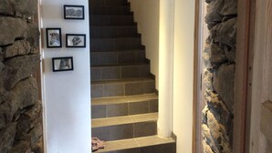 Eine Treppe mit Steinwänden, gerahmten Bildern an der Wand und einem Holzregal.