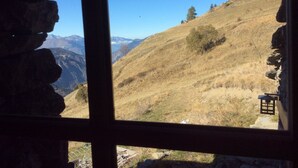 Blick durch ein Fenster auf eine Berglandschaft mit blauem Himmel.