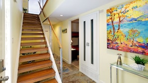 A staircase with wooden steps and a glass railing, leading to a room with a bed and a red headboard. - Carolyn's Bay View Home (San Diego)