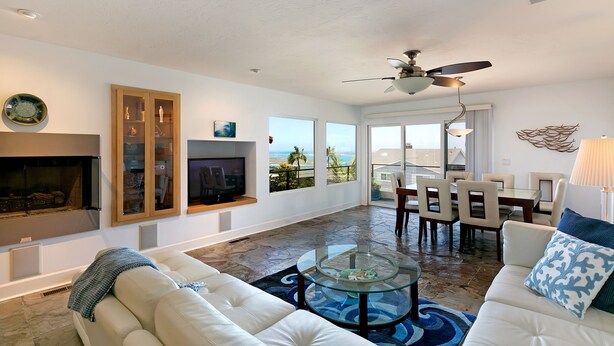 A spacious living room with a fireplace, a glass coffee table, and a view of the ocean. - Carolyn's Bay View Home (San Diego)