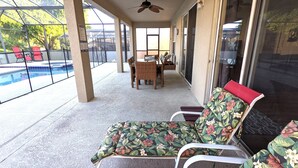 A covered patio area with a pool, wicker furniture, and a ceiling fan. - Best Vacation Ever! Home Away From Home! (Kissimmee)
