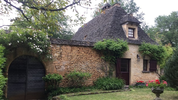 Una cabaña de piedra con techo de paja, una puerta de madera y un ventanal pequeño.