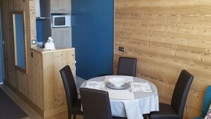 Een eetruimte met een ronde tafel, vier stoelen en een witte tafelkleed.