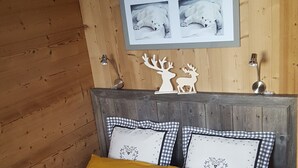 Een bed met twee gele kussens en een bruine deken, een houten hoofdbord en een lijst met een foto van ijsberen aan de muur.
