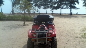 A red quad bike parked on sandy ground with trees in the background. - Between sea and lagoon, Keur Océan, a "PARADISE" (Pointe sarene)