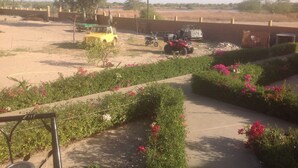 A paved pathway with flower beds, a yellow vehicle, and a red ATV in a rural setting. - Between sea and lagoon, Keur Océan, a "PARADISE" (Pointe sarene)