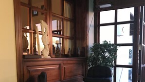 Een hoek met twee barkrukken, een potplant en een raam met decoratieve objecten.