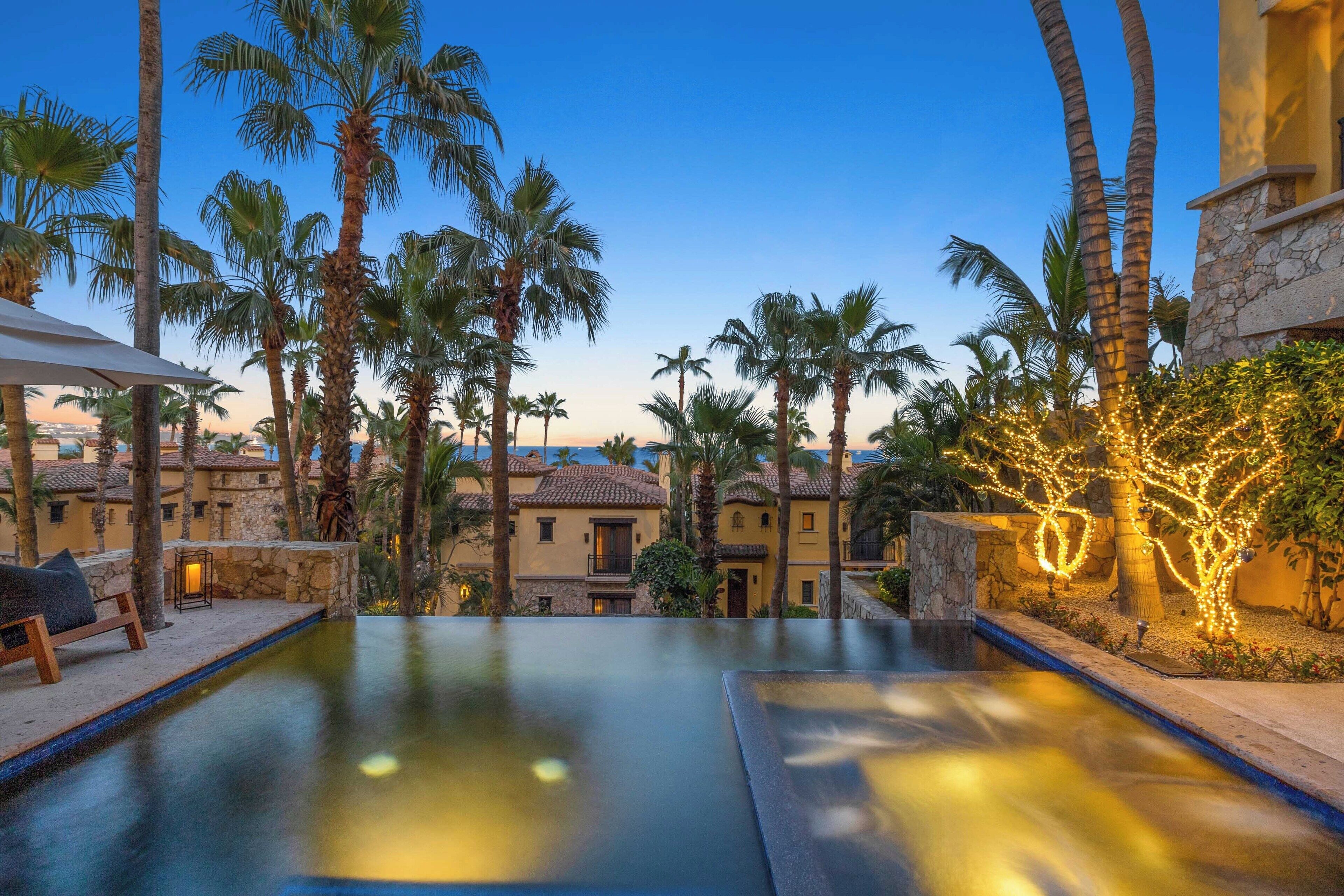 A pool area with a view of a building and palm trees.