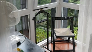 Ein Zimmer mit einem großen Fenster, einem Sessel, einem kleinen Tisch und einem gelben Behälter.
